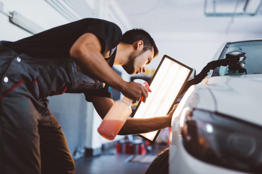 Car mechanic working to remove dent in workshop.